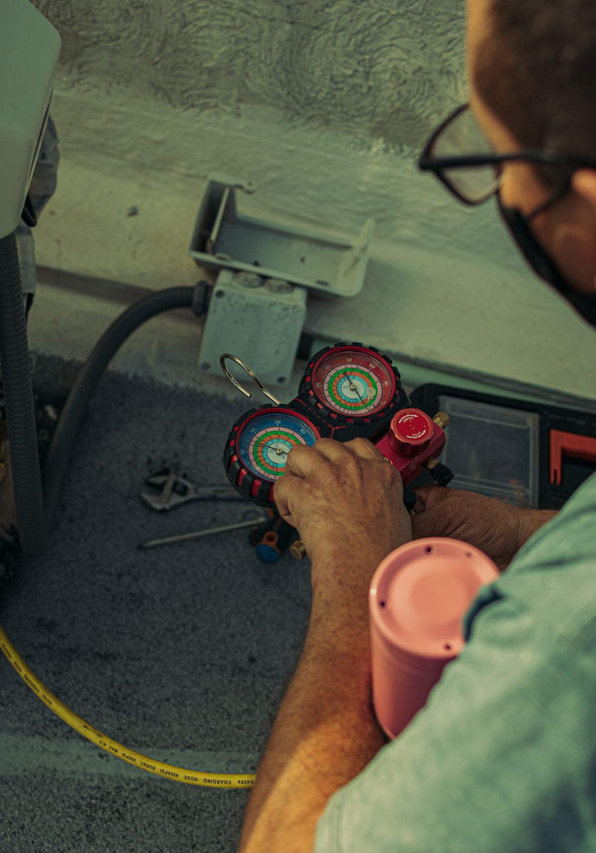 Technician checking refrigerant pressures with a manifold gauge on a residential AC unit